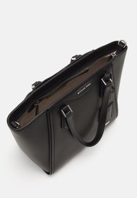 Schwarze Lederhandtasche mit silbernem Zubehör, Reißverschluss, zwei kurzen Griffen und einer strukturierten Oberfläche. Das Innere ist beige mit Logodetail.