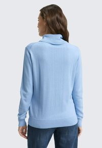 Lichtblauwe trui met een hoge kraag, geribbelde manchetten en zoom. Gemaakt van zachte stof, met een gladde textuur en een slim-fit ontwerp.