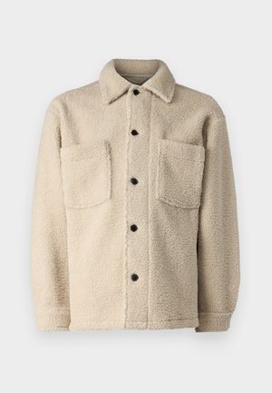 Beige, fleece-sisustettu takki, jossa on kaulus, kaksi etutaskua ja mustat nappikiinnitykset. Teksturoitu kangas näkyvillä ompelutiedoilla.