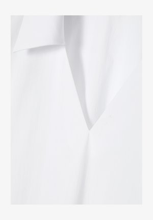 Valge kangas pehme ja sileda tekstuuriga, sügava V-kaelusega ja nurga all klapiga. Minimalistlik disain puhaste joontega.