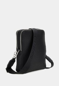 Schwarze Leder-Crossbody-Tasche mit einer strukturierten Oberfläche, dualem Reißverschluss und verstellbarem Tragegurt mit Logo-Akzent. Kompakte rechteckige Form.