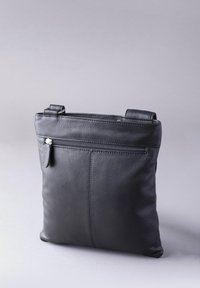 Black leather crossbody bag with a textured finish. Features a front zipper pocket and adjustable shoulder strap. Minimalist design.