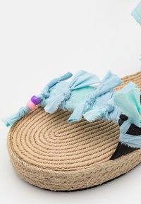 Blå tyg espadrillosandaler med volangdetaljer och färgglada pärlor; soles av jute rep med en texturerad, vävd mönster.
