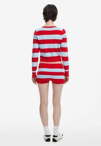 Pulover cu dungi roșii și bleu deschis, set cu fustă asortată. Textură tricotată, design ajustat, mâneci lungi și siluetă cropped.