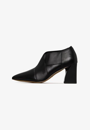 Zapato de tacón alto de cuero negro con punta afilada, paneles texturizados y un tacón grueso. Acabado suave con un color sólido y un diseño minimalista.