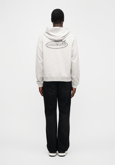 Šedá mikina s kapucí a logem na zádech, doplněná černými džíny a bílými teniskami, zobrazena zezadu. Bavlněný materiál s hladkou texturou.
