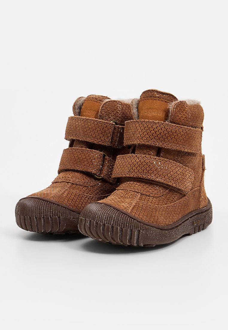 Braune Knöchelstiefel mit Klettverschlüssen, strukturiertem Obermaterial, weicher Fellfutter und Gummisohle. Besitzt ein kreisförmiges Muster auf dem Material.