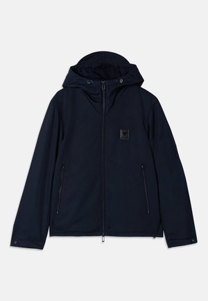 Navy hooded jacket with a front zip closure, two zippered side pockets, and a textured logo patch on the chest. Smooth fabric finish.