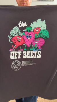 T-shirt gráfico com vegetais em desenho animado: rabanetes rosa e vermelho com folhas verdes, tecido preto, texto em branco em destaque a dizer "FORA BATATAS".