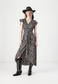Robe noire à fleurs avec des manches courtes et légères, taille cintrée et longueur jusqu'à la cheville ; associée à des bottes de cowboy noires brodées et un chapeau à large bord.