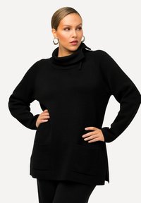 Schwarzer übergroßer Pullover mit hohem Kragen, zwei Seitentaschen und seitlichen Schlitzungen. Aus strukturiertem Stoff gefertigt, mit langen Ärmeln.