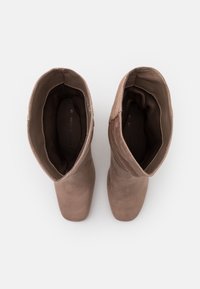 Brown suede ankle boots with a smooth texture, square toe, and folded collar. The interior is lined with a contrasting brown material.