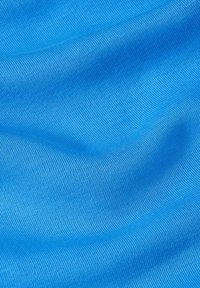 Mjuk blått tyg med synlig fin stickad textur och försiktiga veck som skapar subtila skuggor och höjdpunkter.