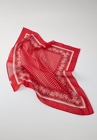 Écharpe rouge en tissu léger, avec une bordure paisley et un motif à pois. Bordée d'une finition contrastante crème.