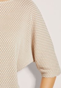 Lichtbeige gebreide top met een gestructureerd honingraatpatroon, ruime pasvorm en driekwart mouwen. Zachte stof, minimalistische details.