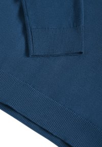 Tissu tricoté bleu en gros plan montrant les détails côtelés du poignet et de l'ourlet sur un vêtement à manches longues.