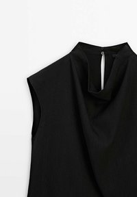 Black sleeveless top featuring a draped neckline, smooth texture, and a button closure at the back. Simple, minimalist design.