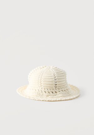 Chapeau bob crocheté de couleur crème avec un motif de points texturé et un bord légèrement souple.