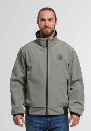 Grau weiche Schale Jacke mit hohem Kragen, schwarzen Akzenten, seitlichen Reißverschlusstaschen und einem Logo auf der linken Brust. Besitzt einen glatten, strukturierten Stoff.