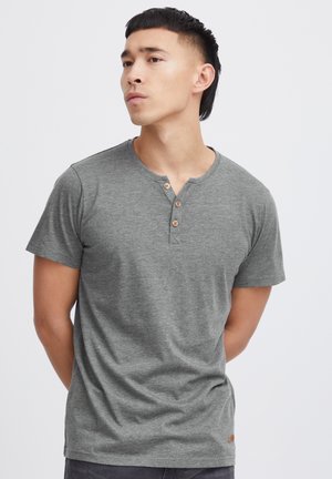 Grå kortærmet henley t-shirt lavet af struktureret stof, med en rund halsudskæring, tre træknapper og et lille lædermærke på kanten.
