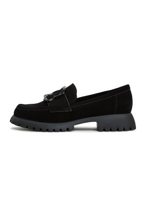 Black suede loafers with a chunky black rubber sole, featuring a decorative strap and silver-toned hardware accent.