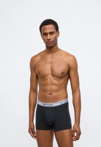 Boxers en coton noir avec une ceinture Nike grise, présentant un design ajusté et une texture lisse.