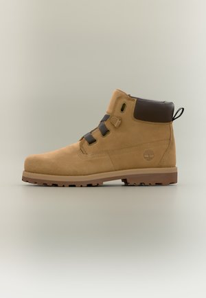Bottine en cuir fauve avec col matelassé noir, lacets noirs, semelle robuste et logo Timberland sur le côté.