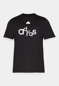 Svart bomull t-shirt med en stor vit grafik med ordet "adidas" i stiliserad lettering på framsidan. Klassisk design med rund hals.