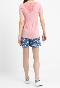 Rosa kortärmad topp med en spets V-back, i kombination med bl�å blommönstrade shorts. Vita sneakers fullbordar outfiten.