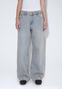 Ljusblå vida jeans i denim, med en klassisk femfickdesign och en något blekt finish. Bärs med svarta skor.