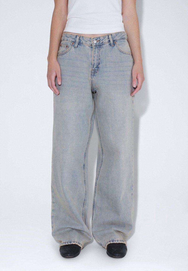 Ljusblå vida jeans i denim, med en klassisk femfickdesign och en något blekt finish. Bärs med svarta skor.
