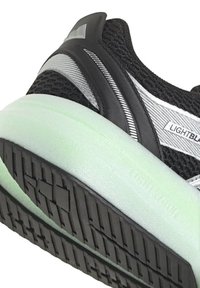 Scarpa sportiva nera con tomaia in mesh, dettagli argentati e suola in gomma verde chiaro. Presenta un battistrada testurizzato per una migliore aderenza.