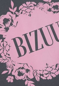 Zwarte stof met een roze bloemmotief en het woord "BIZUU" in vetgedrukte, hoofdletters in het midden, wat een opvallend contrast creëert.