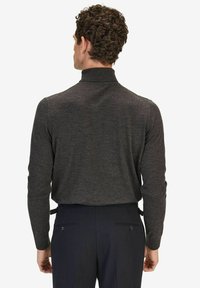 Mörkgrå långärmad tröja med hög krage, tillverkad av ett mjukt material. Bärs med skräddarsydda marinblå byxor med bakfickor.