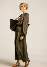 Olivgrön satin långärmad klänning med rynkade manschetter och figurnära midja. Kombineras med en svart tote-väska och bruna klackmules.