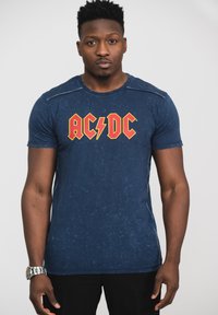 Navy blue short-sleeve t-shirt with a distressed texture and red AC/DC logo. Features a round neck and subtle stitching accents.