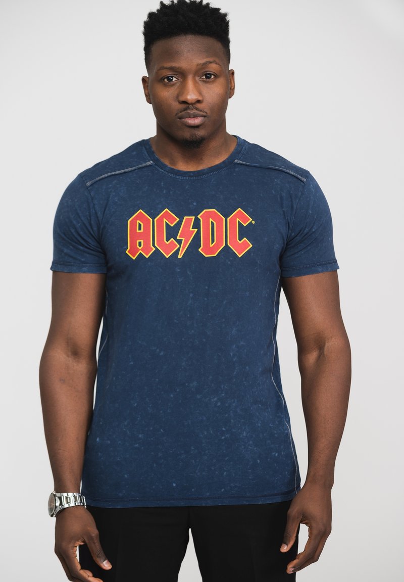 Navy blue short-sleeve t-shirt with a distressed texture and red AC/DC logo. Features a round neck and subtle stitching accents.