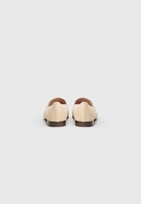 Light beige suede shoes with a rounded toe and low heel, featuring simple design and smooth texture. No visible hardware or accents.