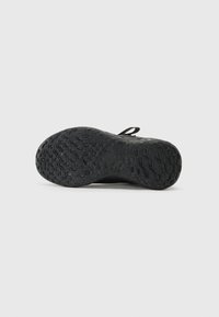 Semelle de chaussure de sport noire en caoutchouc texturé, dotée de rainures flexibles et d'un motif antidérapant pour l'adhérence. Bords renforcés et une languette.