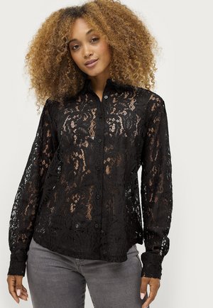 Zwarte kanten blouse met een knoopsluiting aan de voorkant, lange mouwen, bloempatronen en een doorschijnende textuur, gecombineerd met grijze jeans.