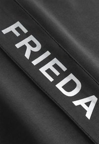 Zwarte stof met een gladde textuur, waarop het woord "FRIEDA" in grote, metallic zilveren letters horizontaal over het materiaal is afgedrukt.