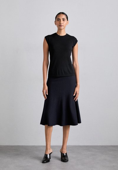 Black sleeveless top paired with a knee-length black flared skirt. Smooth texture, fitted waist, and simple design. Black heeled mules.