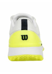 Weißer Sportschuh mit einer strukturierten Oberseite, auffälliger gelber Zwischensohle, schwarzen Streifen-Details und einem markanten schwarzen Logo auf der Ferse.