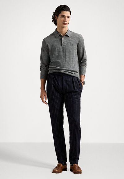 Pilkos ilgas rankovėmis polo marškiniai ir tamsiai mėlyni dryžuoti kelnės, papildomi rudi odiniai bateliai. Paprastas dizainas su klasikinio kirpimo ir tekstūra.