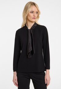 Schwarzes Langarmoberteil mit einer glatten, weichen Textur und einem Satin-Schal-Detail am Hals. Schlichtes Design mit geradem Schnitt.