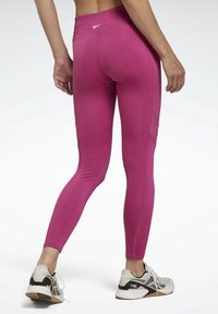 Leggings ajustés taille haute en rose vif, fabriqués à partir d'un tissu lisse et extensible. Présente des accents en panneaux latéraux avec des détails texturés.