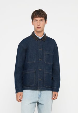 Dark blue denim jacket with a brown collar, front button closure, and two large front pockets. Soft texture and relaxed fit.
