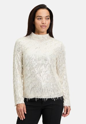 Langärmlige Bluse mit hohem Kragen in Off-White, mit einem strukturierten Fransen-Design, das metallische Akzente aufweist und einen geraden Saum hat.