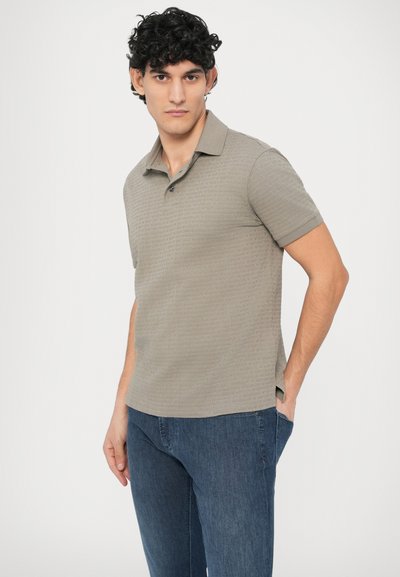 Polokošeľa s krátkym rukávom v tlmenej sivej farbe s textúrovaným vzorom. Má klasický golier a zapínanie na tri gombíky, v kombinácii s modrými džínami.