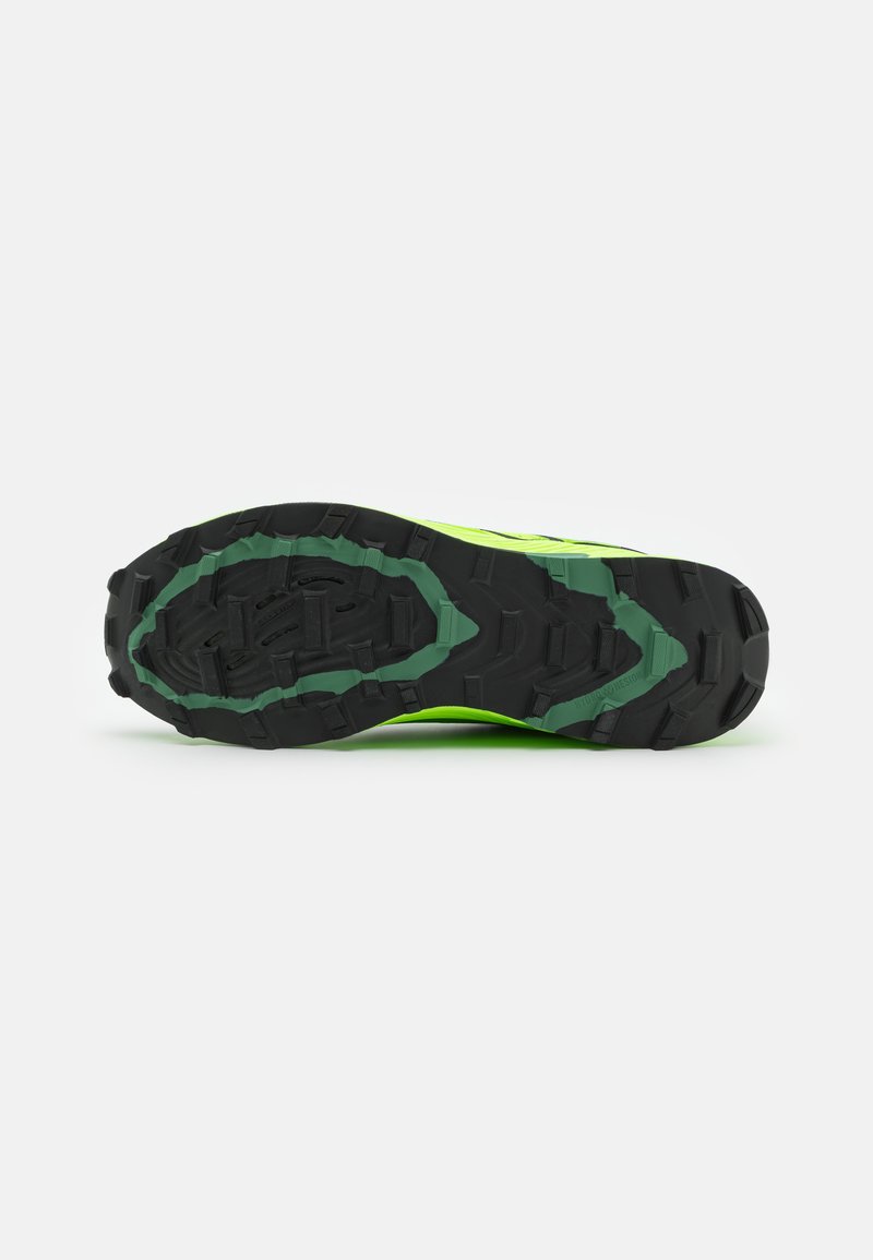 Suela de zapatilla de trail running en negro y verde vibrante, con tacos profundos para tracción y un diseño texturizado para durabilidad.